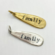 Two silver and gold charms with the word "family" engraved on them. The charms are teardrop shaped and have a loop at the top for attaching to a necklace or bracelet.