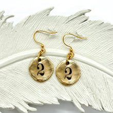 A pair of earrings with a round #2 charm. The 2 is ink stamped & sealed in resin and they are in a gold finish.