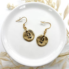 A pair of earrings with a round #2 charm. The 2 is ink stamped & sealed in resin and they are in a gold finish.
