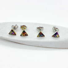 Four handmade geometric triangle stud earrings with colorful faux druzy / crushed crystal inlay in shades of purple, blue, pink, and gold. Displayed on a textured white ceramic block. Perfect minimalist jewelry gift, dainty boho earrings, and colorful everyday studs with hypoallergenic silver posts.