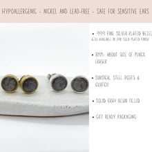 Product infographic for handmade stud earrings on a light cream background. The left side shows two pairs of round, gray resin-filled earrings—one pair with gold bezels and one with silver bezels—resting on a white display block. A top pink banner reads: 'HYPOALLERGENIC - NICKEL AND LEAD-FREE - SAFE FOR SENSITIVE EARS.' Bullet points on the right detail the specifications: .999 fine silver-plated bezel (or 24K gold), 8mm size, surgical steel posts & clutch, and gift-ready packaging.&quot