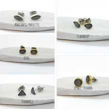 A collage showcasing five geometric styles of handmade charcoal gray glitter resin stud earrings with gold or silver bezels. Each pair rests on a white textured surface with text labels: Marquise/Navette, Teardrop, Oval, Triangle, and Small Round. The dark gray glass flakes create a subtle shimmer inside the resin inlays, featuring surgical steel posts and butterfly clutches designed for sensitive ears.