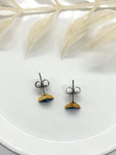 Top view of gold triangle stud earrings with hypoallergenic stainless steel post and clutch backs, displayed on a white ceramic dish with neutral botanical accents. Highlighting quality hardware and earring backings for sensitive ears by Jenica Jewelry.