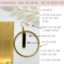 Hypoallergenic 24k Gold Plated Large Hoop Earrings with Black Resin Bar. Size chart shows 2.5 inch length and 50mm width next to a ruler. Infographic details: lightweight, nickel and lead-free, stainless steel ear wires with rubber stoppers. Available in .999 fine silver or 24k gold finish. Perfect for sensitive ears, these geometric minimalist dangles come in gift-ready packaging. Modern boho jewelry for her, handmade high-quality statement earrings.